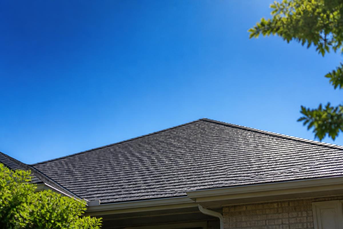 Sun beating down on a dark asphalt shingle roof in summer